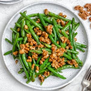 completed Brown Sugar Green Beans [No Bacon] plated on a white plate against a white surface