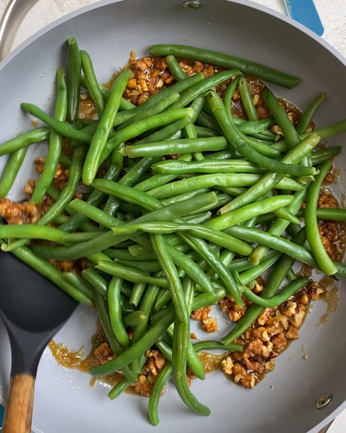Process shot of adding green beans to pan.