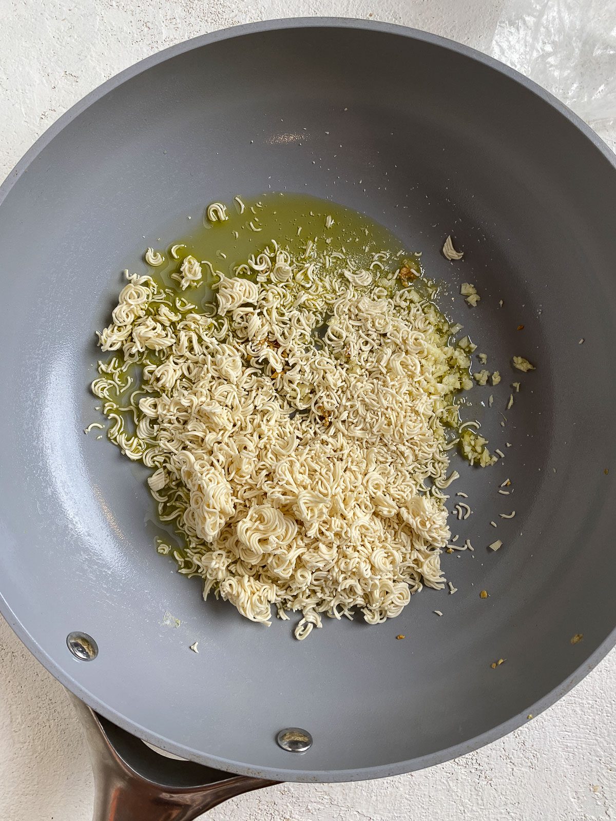 process shot of crushed ramen added to pan