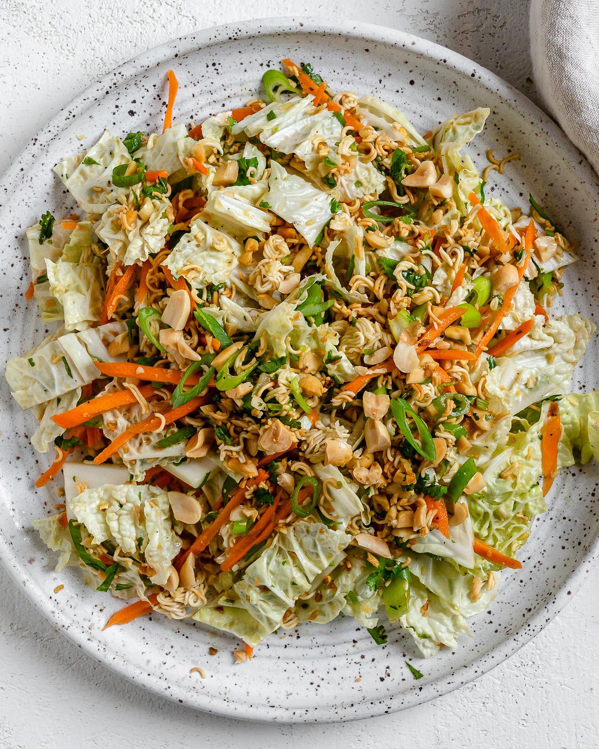 completed Ramen Noodle Cabbage Salad on a white plate against a white background