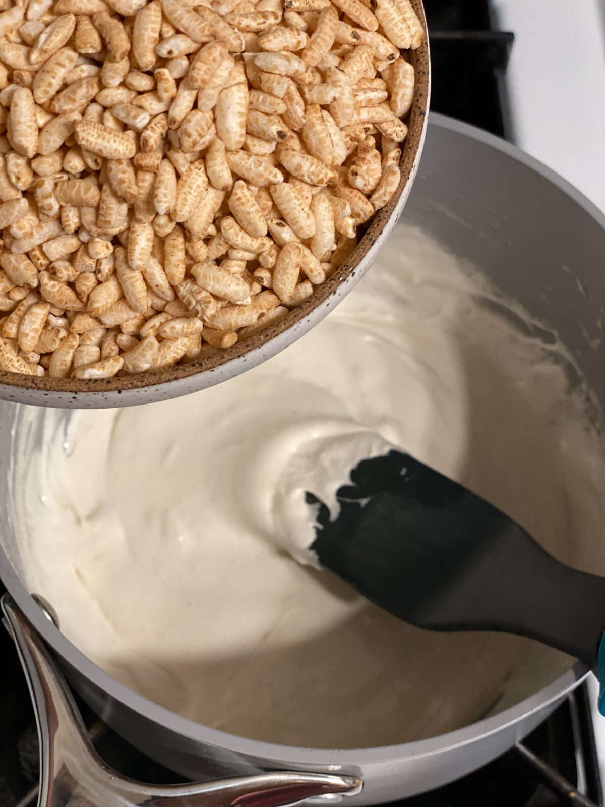 process shot of adding rice krispies to pan