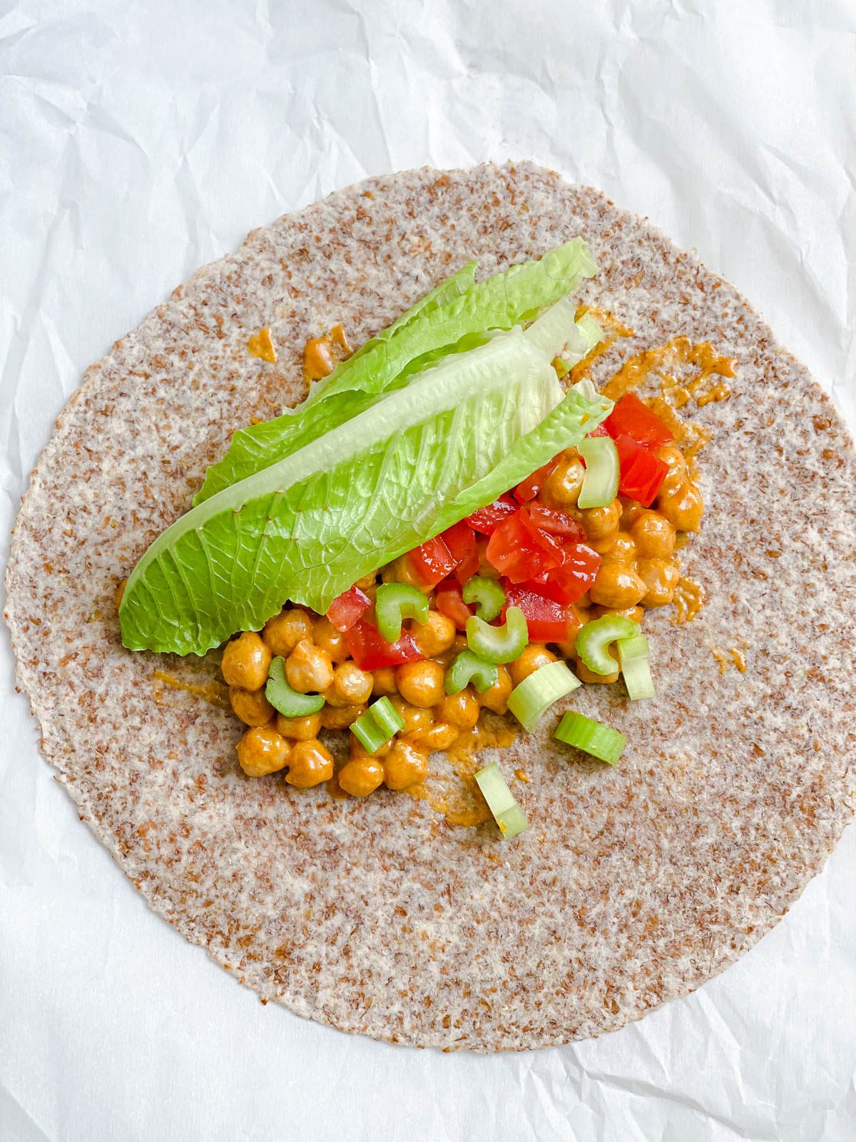 Process shot showing the adding ingredients to wrap against a light surface.