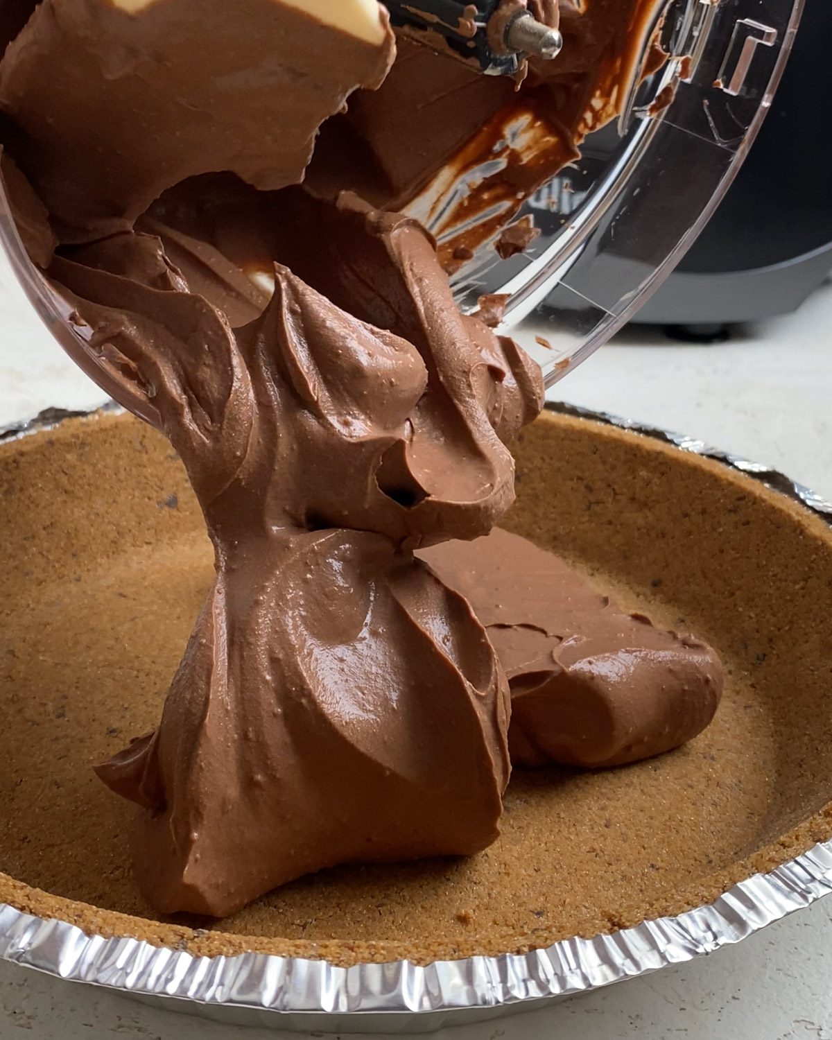 process shot of adding Easy Vegan Chocolate Peanut Butter Pie mixture to pie crust