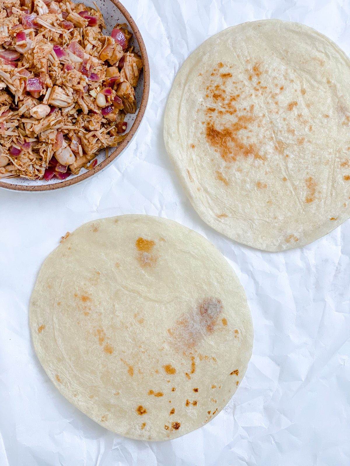 two tortillas alongside bowl of jackfruit carnitas