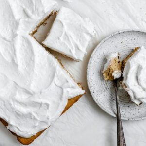 completed Fluffy Vegan Coconut Cake with a piece plated on a white plate