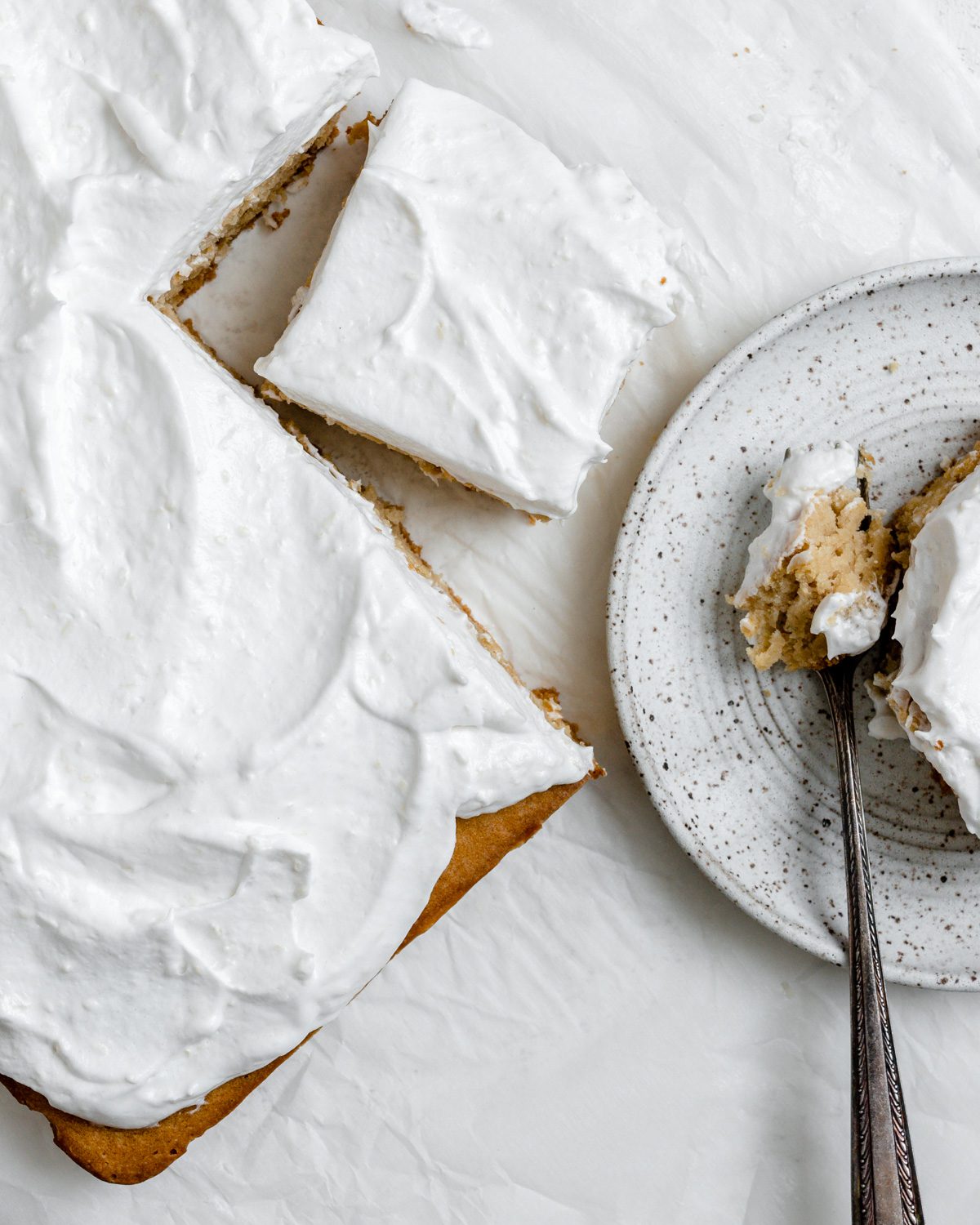 completed Fluffy Vegan Coconut Cake with a piece plated on a white plate