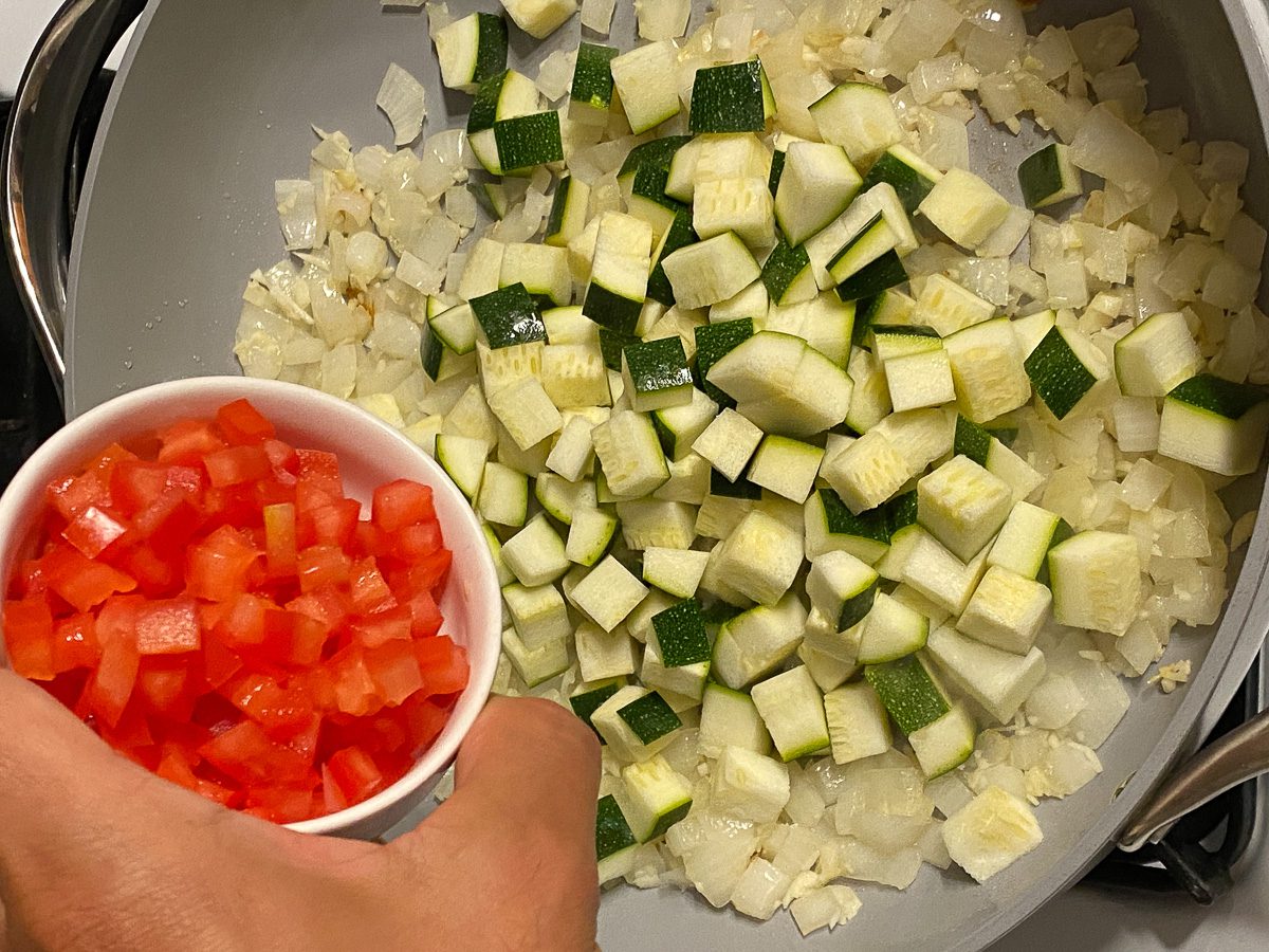process shot of adding tomatoes to pan