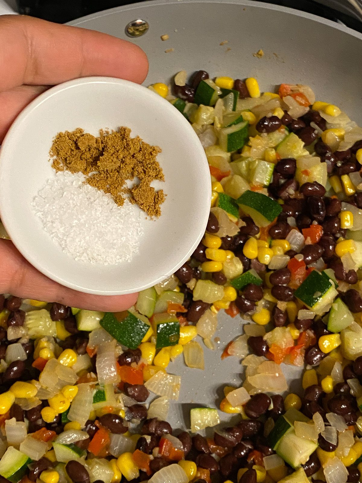 process shot of adding seasonings to pan