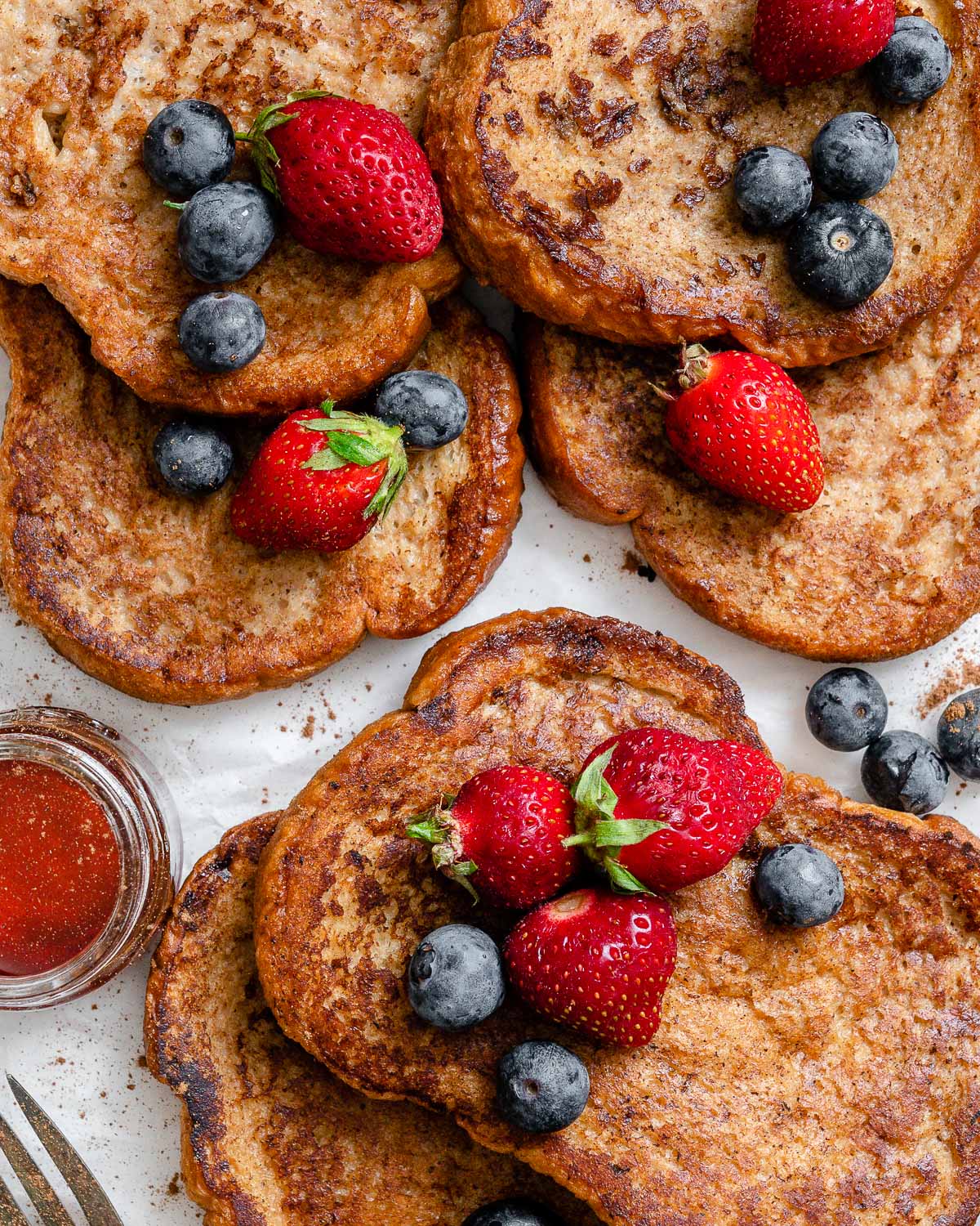 several completed just egg french toast with berries on top against a white surface
