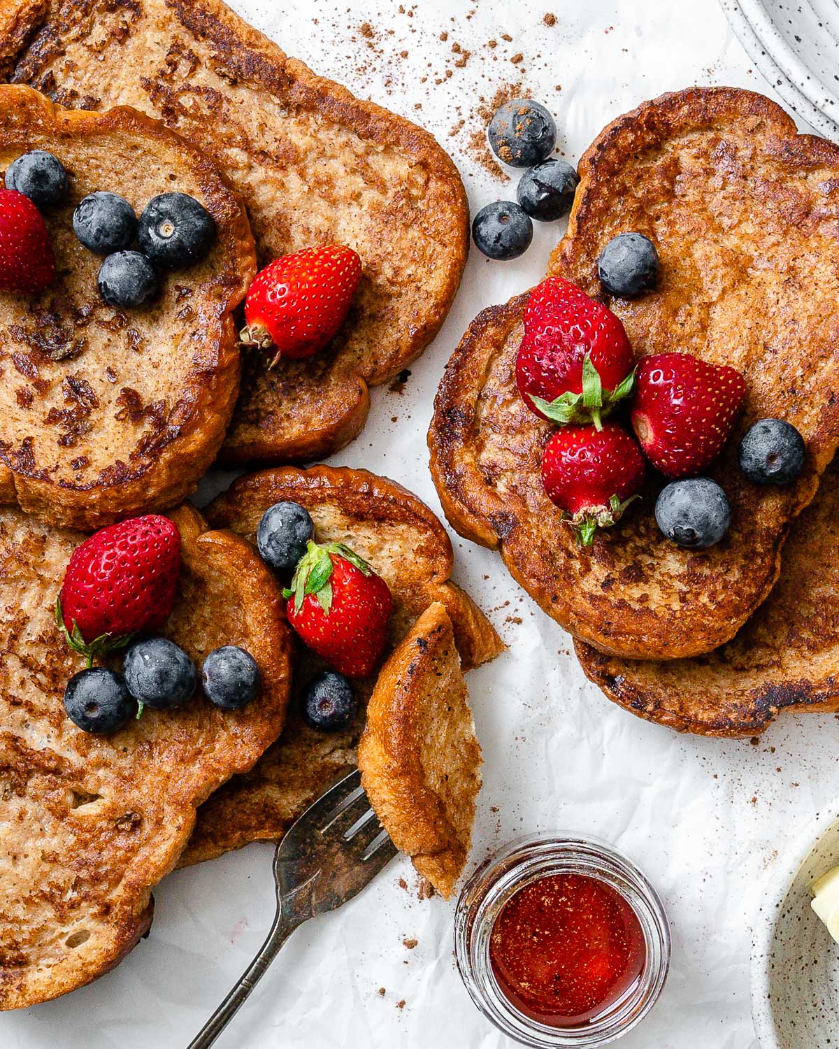 several completed just egg french toast with berries on top against a white surface