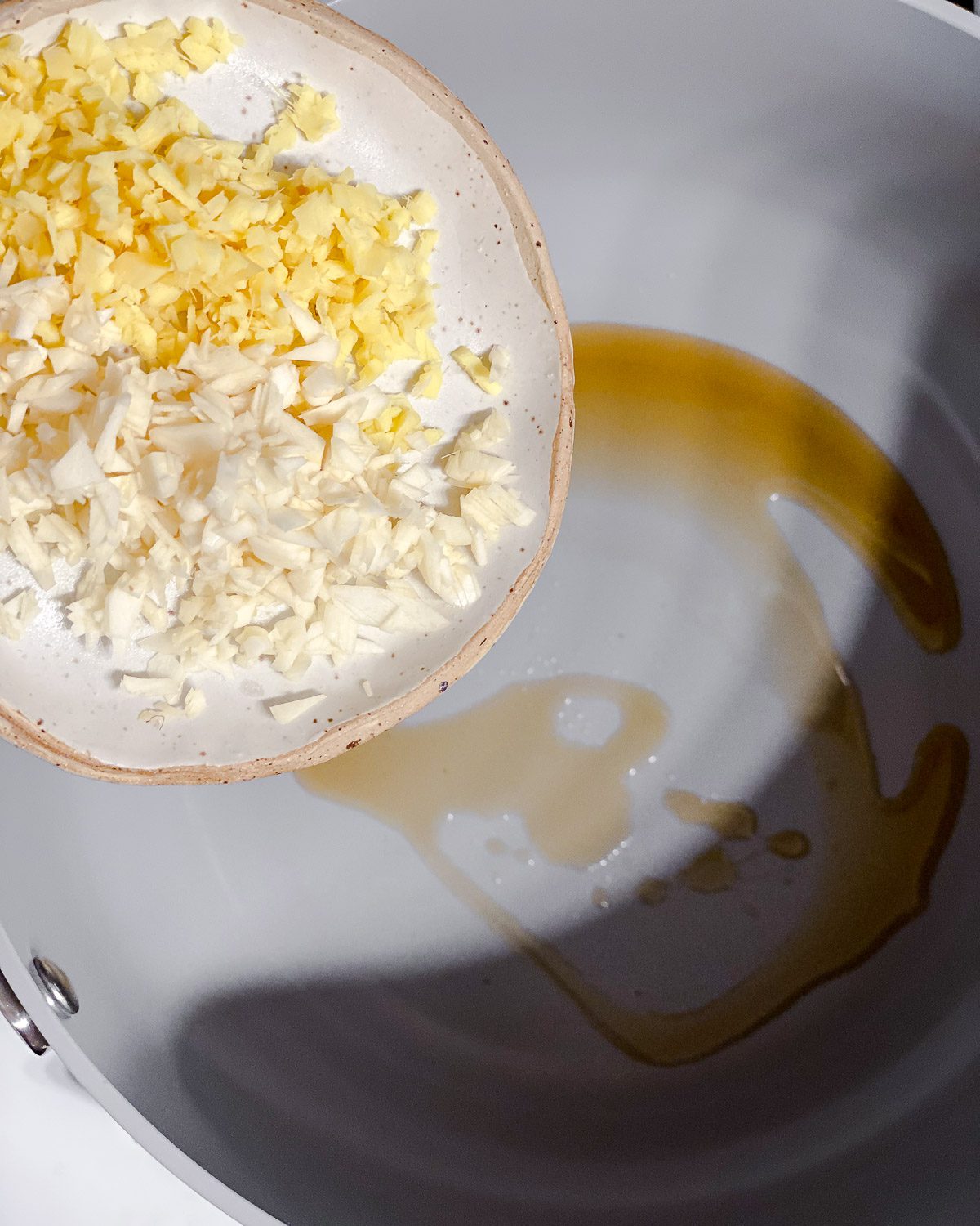 process shot of adding garlic and ginger to skillet
