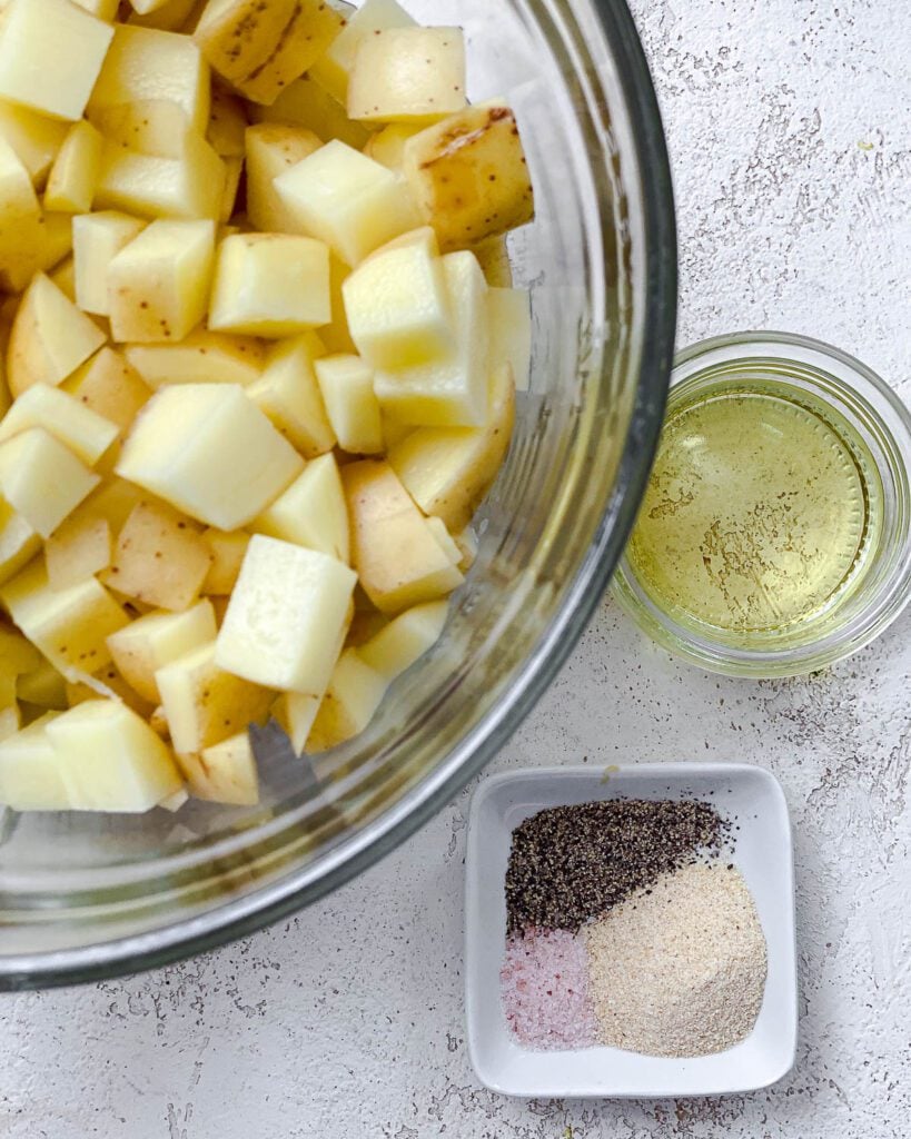 diced potatoes in a bowl alongside spices and oil