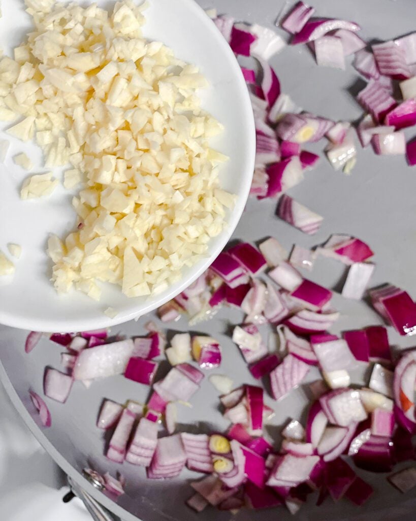 process shot of adding garlic to onion on pan