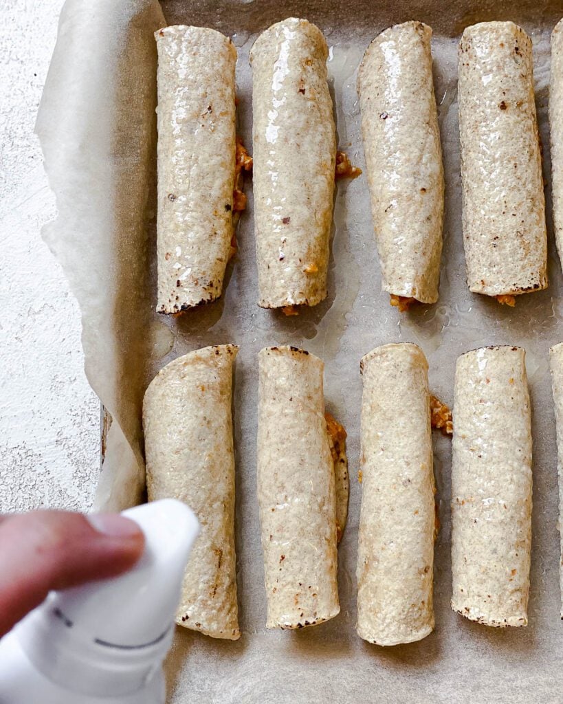 process shot of spraying vegan taquitos with spraying oil