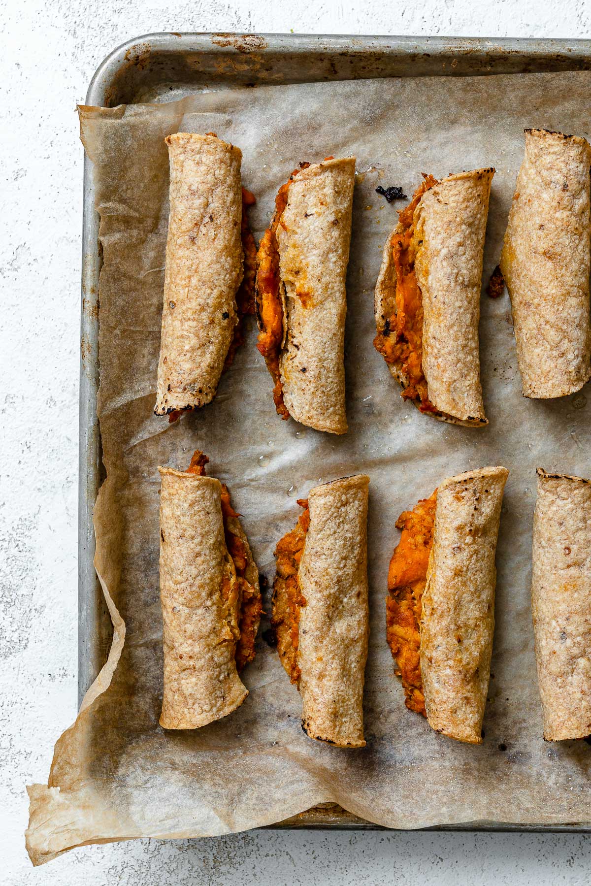 process shot showing post-baked vegan taquitos on baking tray