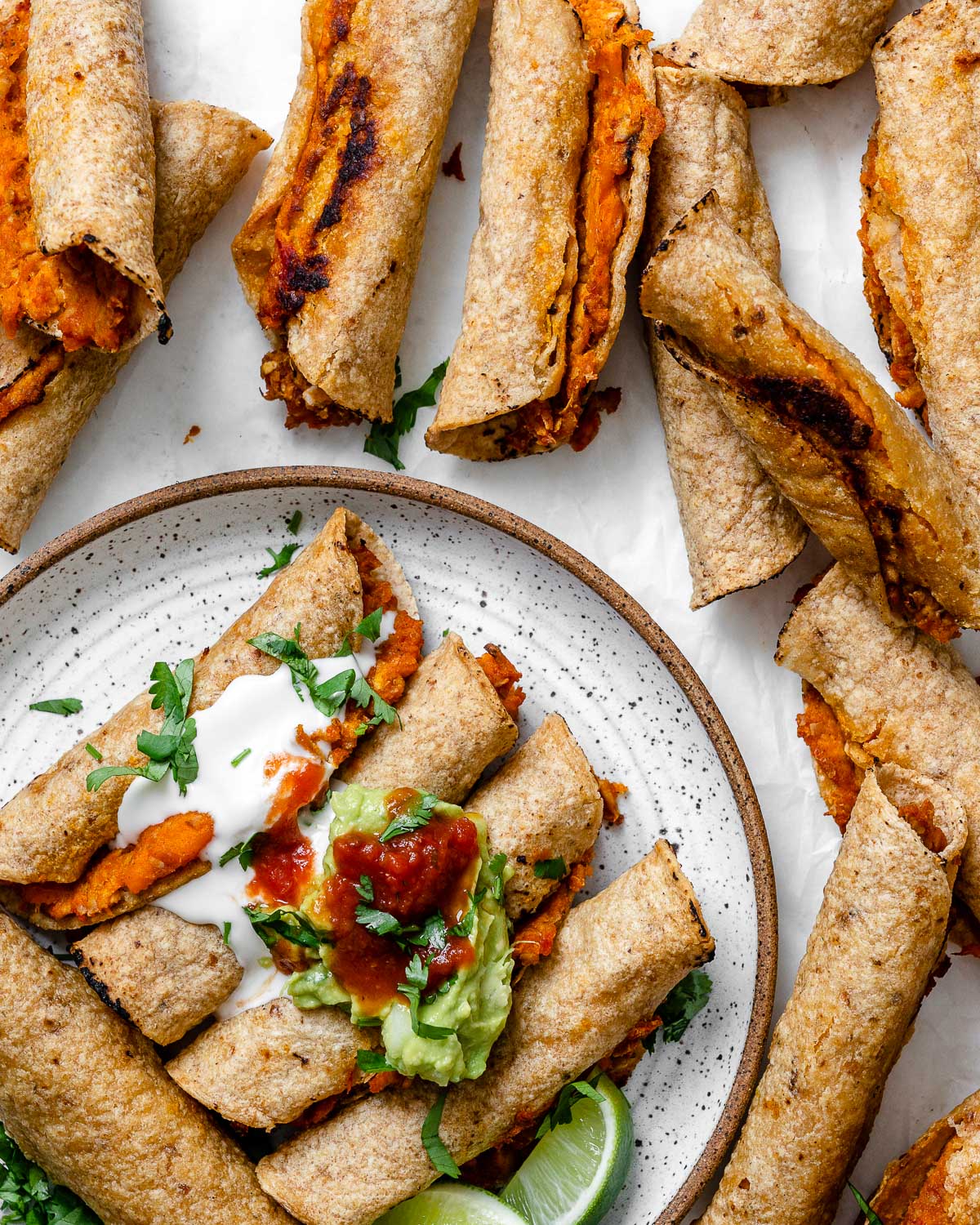 completed Vegan Taquitos against a white surface and topped with garnishes