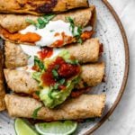 completed Vegan Taquitos against a white surface and topped with garnishes