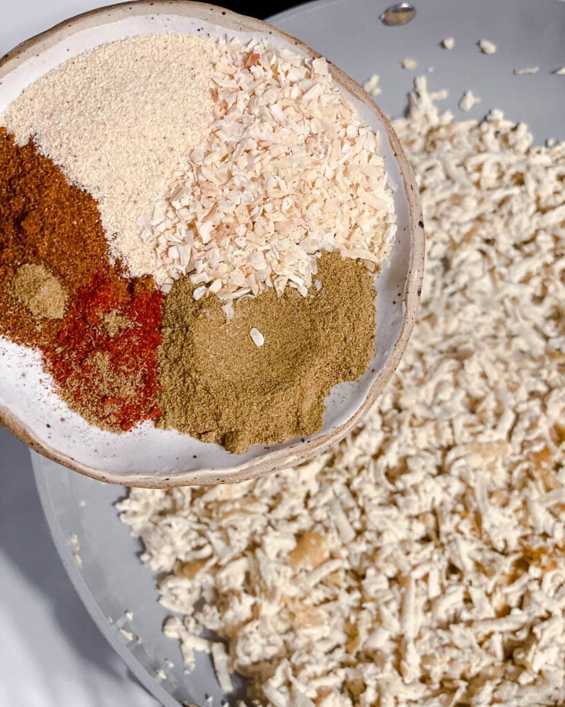 process shot of adding spiced to tofu in pan