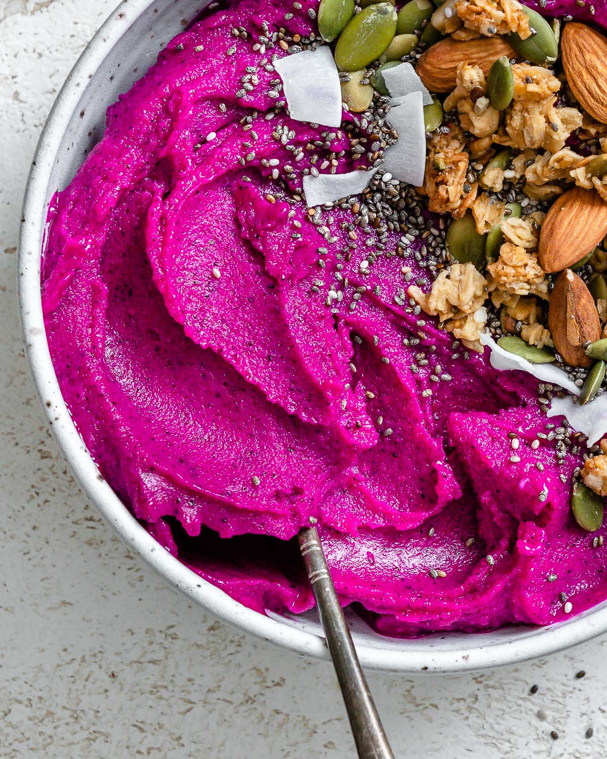 completed Dragon Fruit Smoothie Bowl (Pitaya Bowl) in a bowl against a light surface