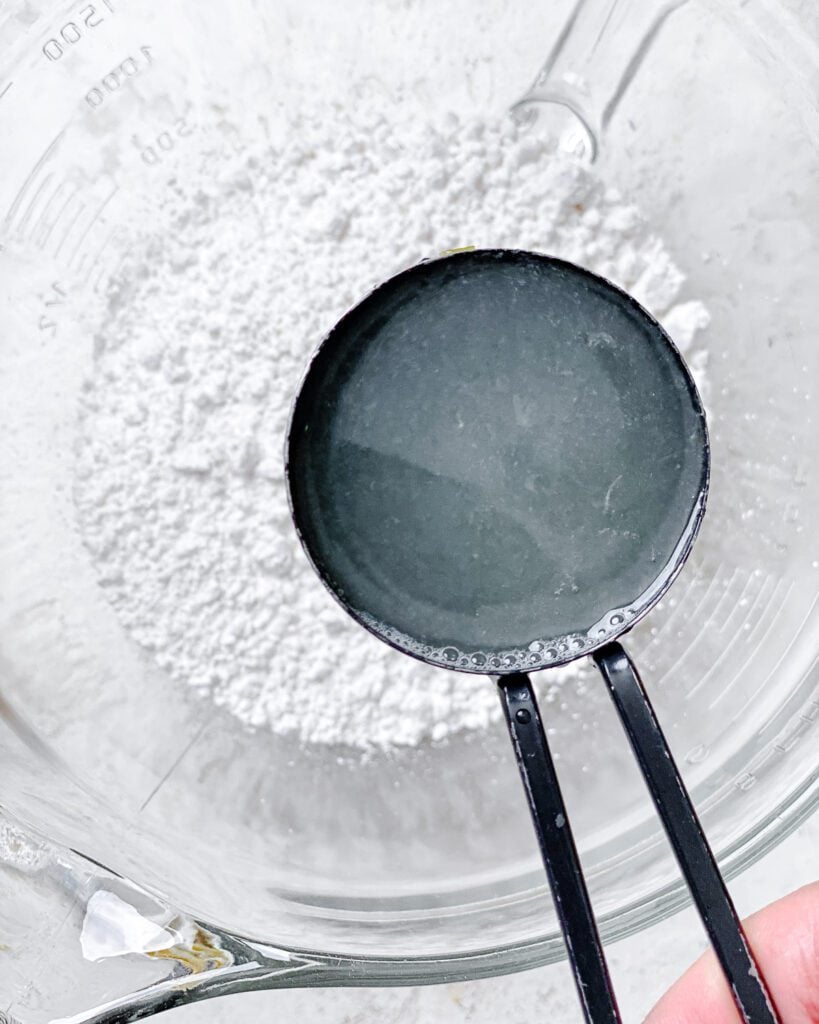 process shot of adding lemon juice to bowl of powdered sugar