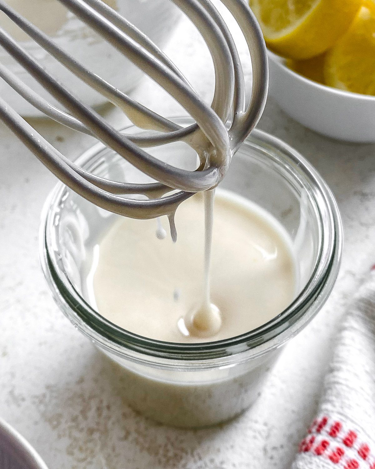 process shot showing lemon glaze falling from whisk in glass container