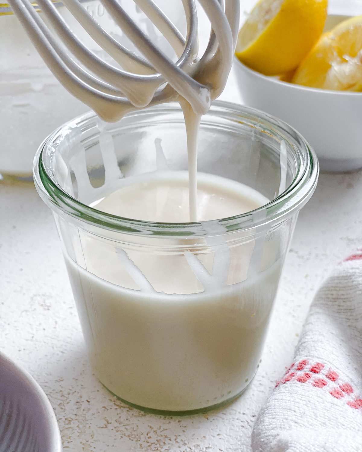 process shot showing lemon glaze falling from whisk in glass container