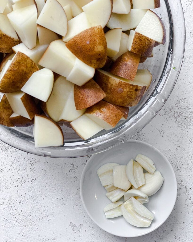 cubed potatoes alongside a bowl of garlic