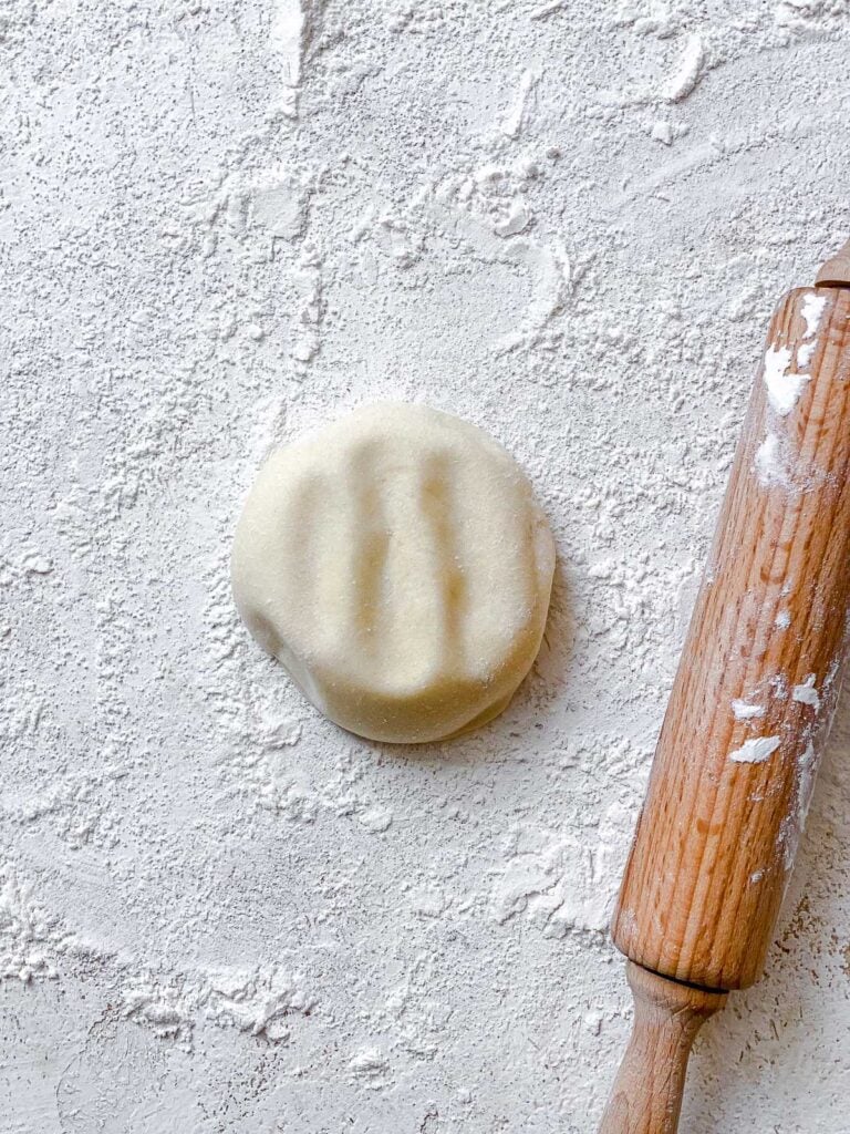 process shot of flattening dough on white floured surface