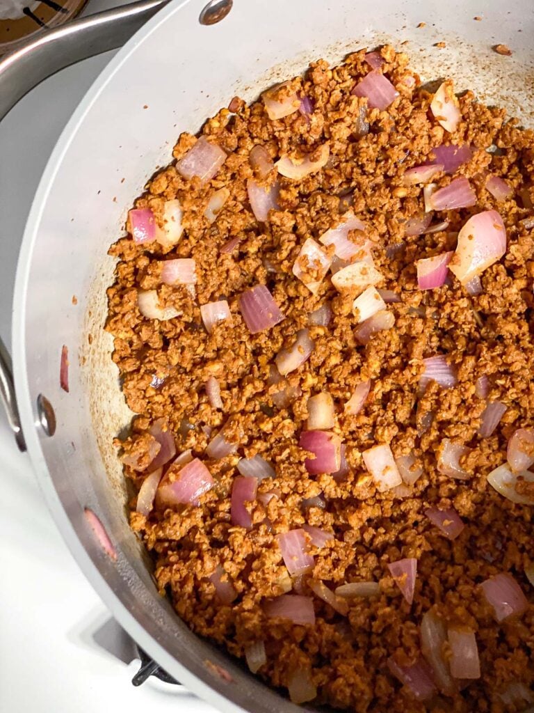 process shot of cooking vegan crumbles and onions in pan