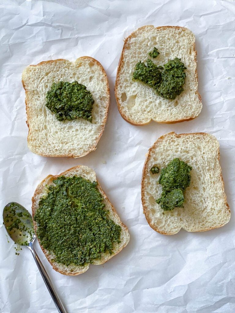 process shot showing addition of pesto on 4 pieces of bread