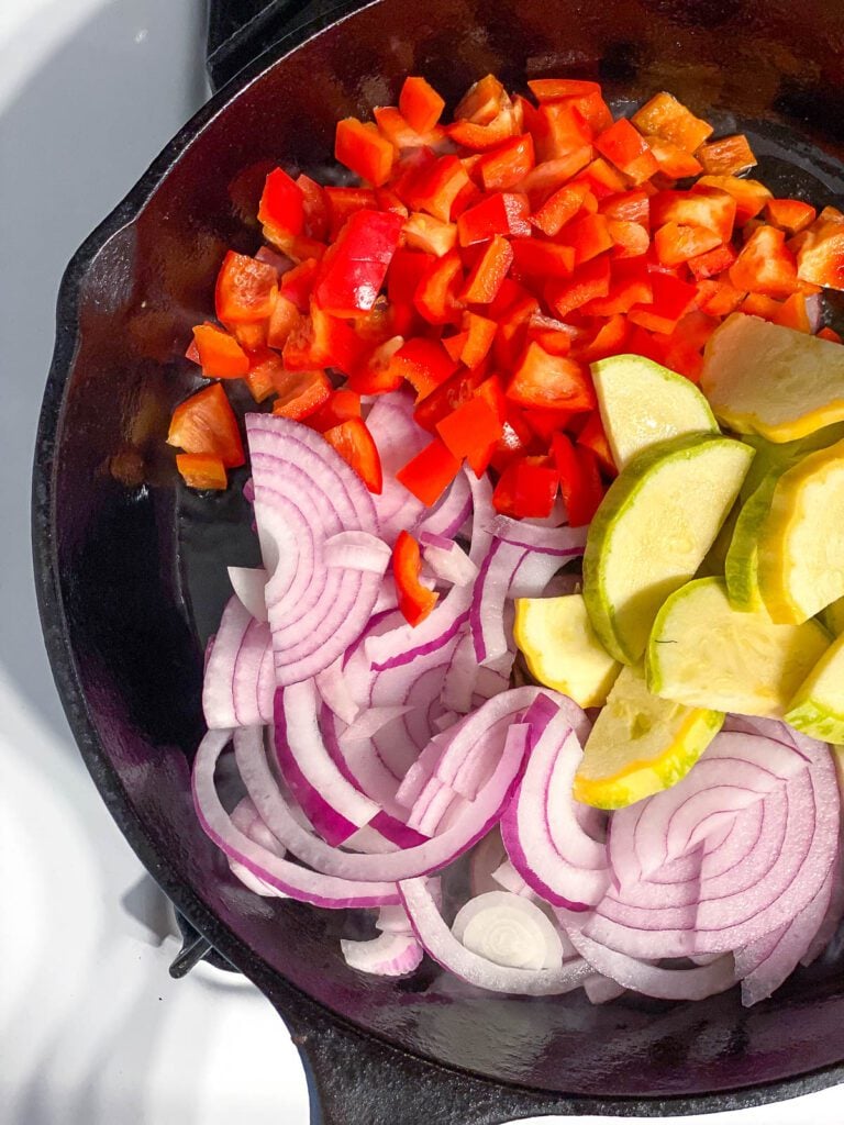 process shot showing the addition of veggies in a skillet
