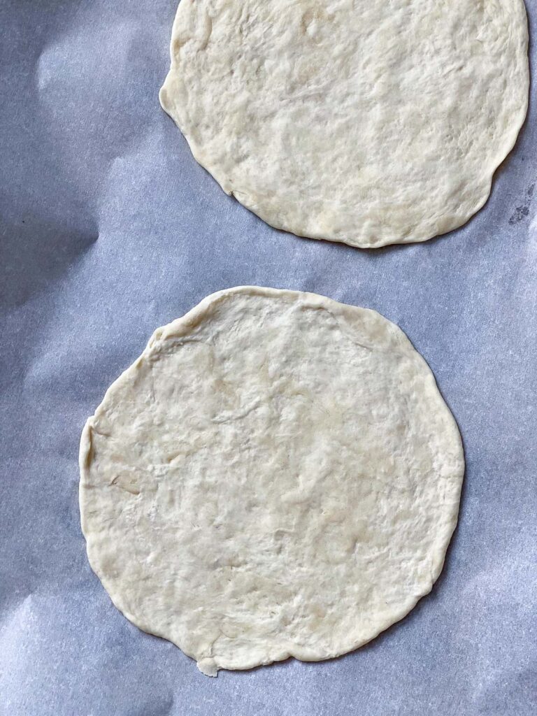 two pieces of rolled out dough against a white surface