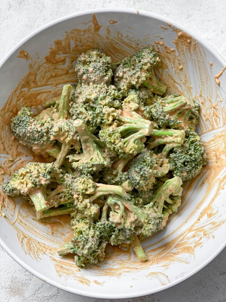 process shot of mixing broccoli in bowl of sauce