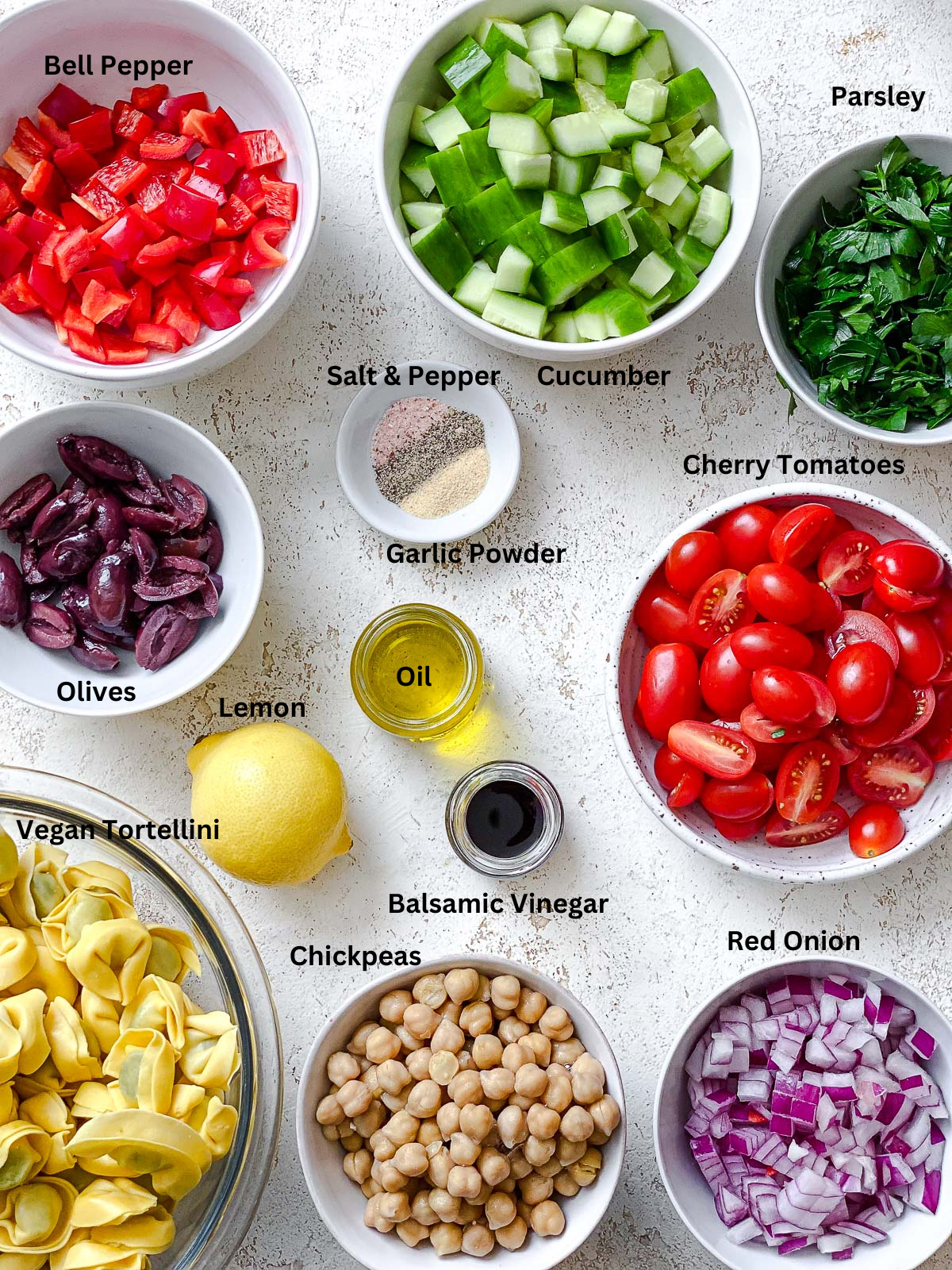 ingredients for Tortellini Pasta Salad measured out on a white surface