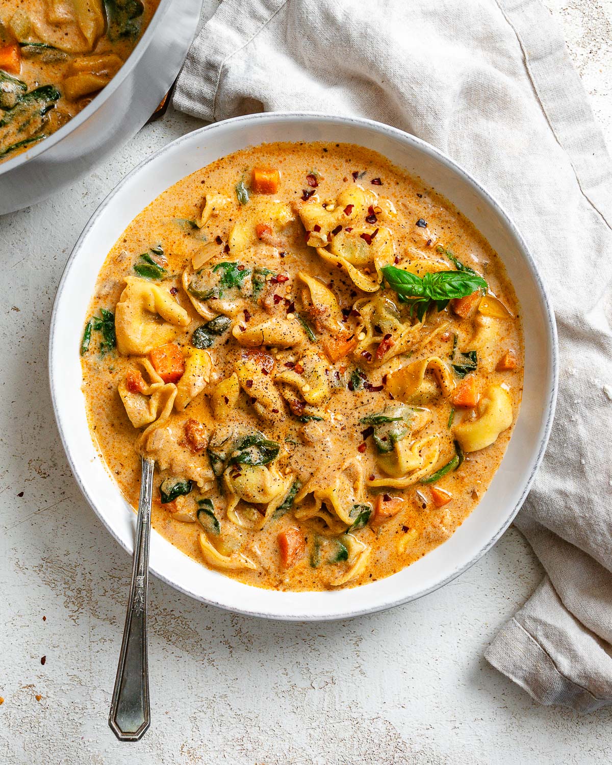 completed Vegan Tortellini Soup in a bowl on a white surface
