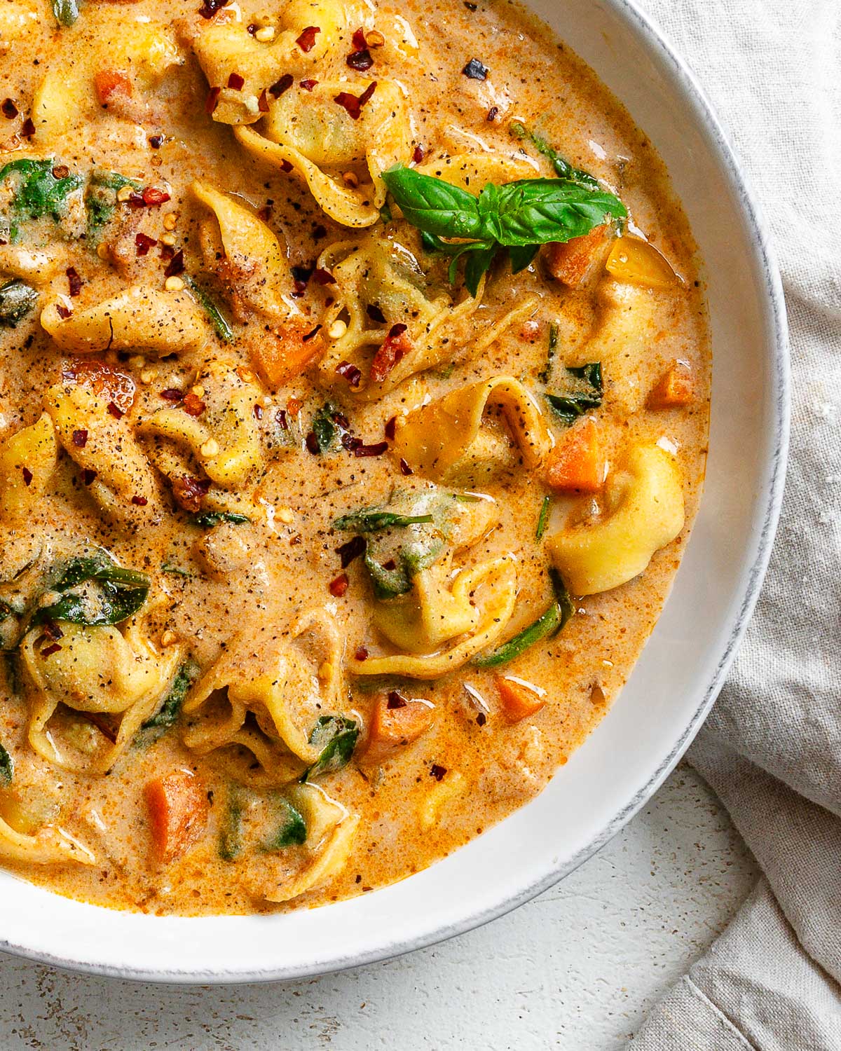 completed Vegan Tortellini Soup in a bowl on a white surface
