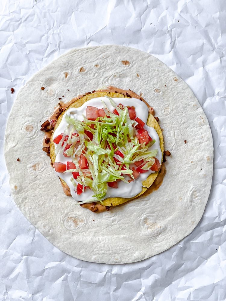 process shot showing adding tomatoes and lettuce to crunchwrap
