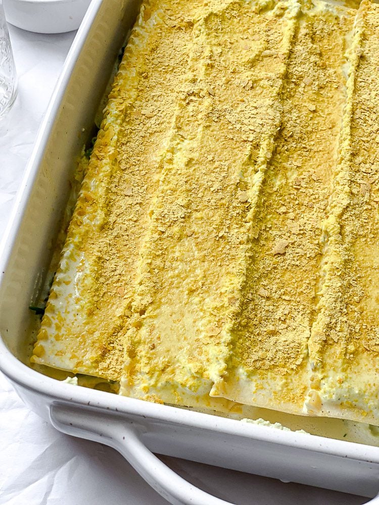 process shot showing nutritional yeast being added to lasagna