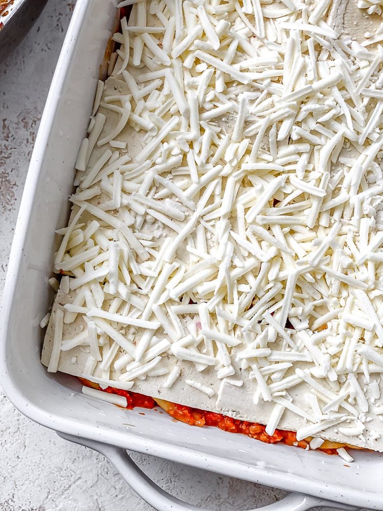 process shot showing vegan cheese added to baking dish