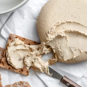 completed Vegan Cheese Ball on bread and on a white surface