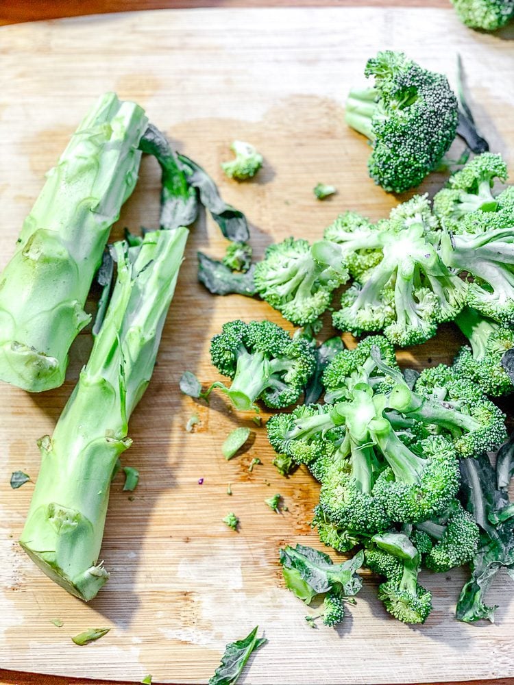 process shot showing cutting broccoli on. cutting board