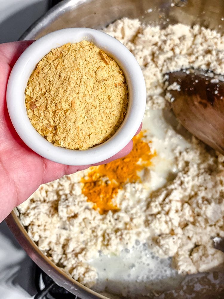 process shot of adding nutritional yeast to pan