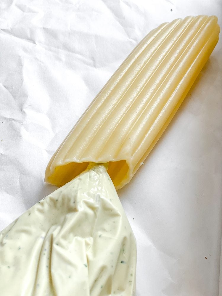 Process shot showing adding tofu ricotta into pasta.