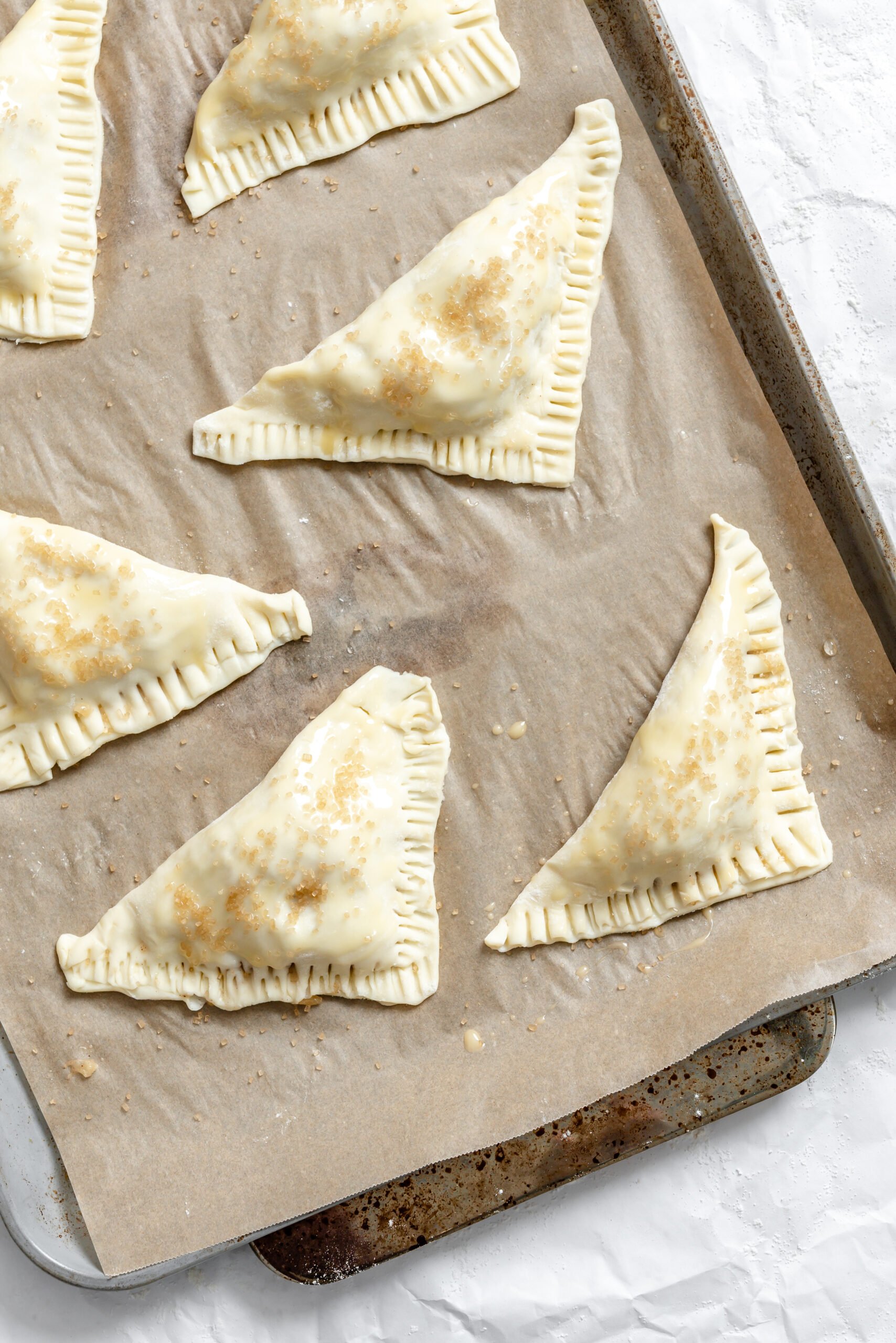 Process shot showing unbaked turnovers on baking sheet.