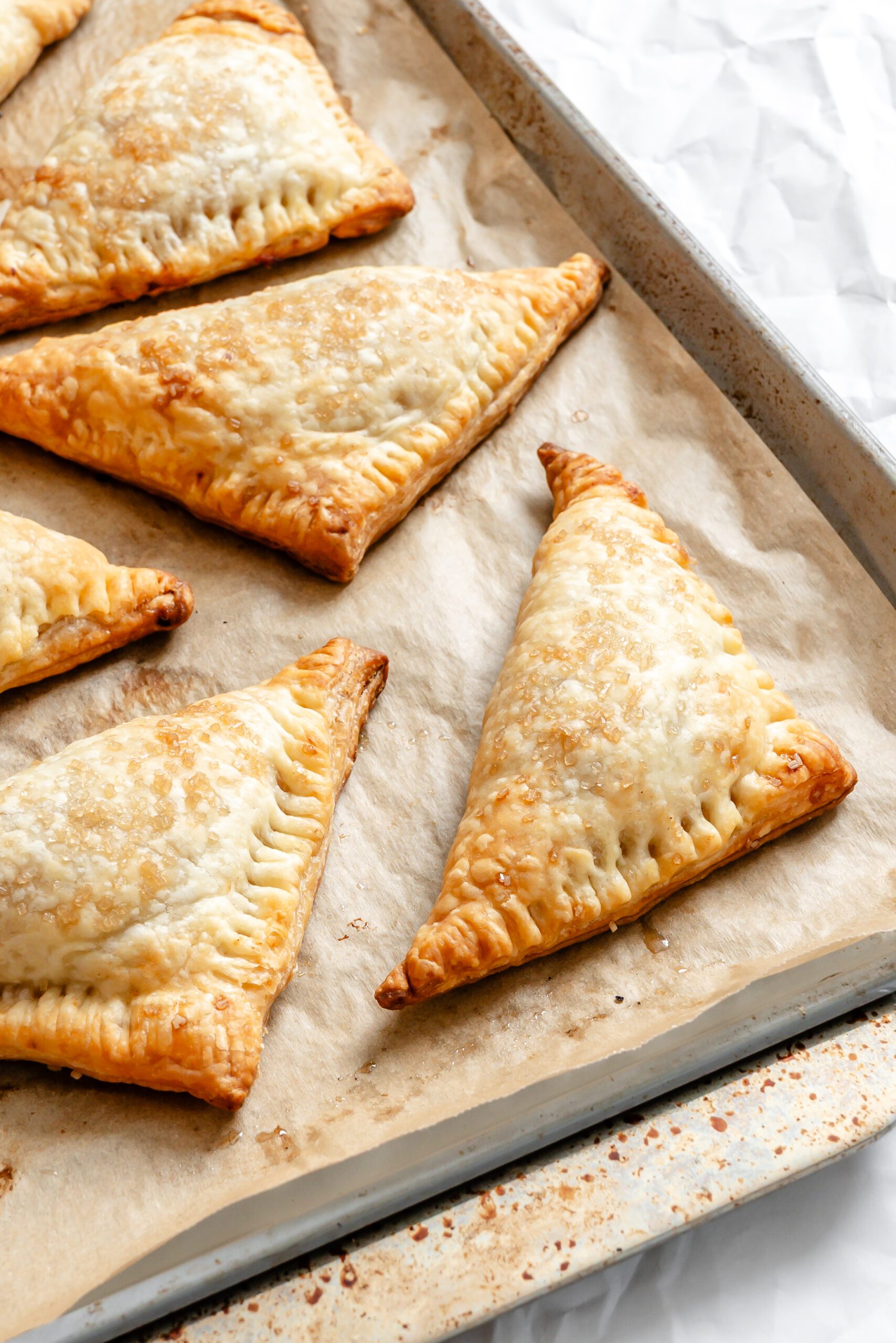 Process shot showing completed Vegan Apple Turnovers on baking sheet.