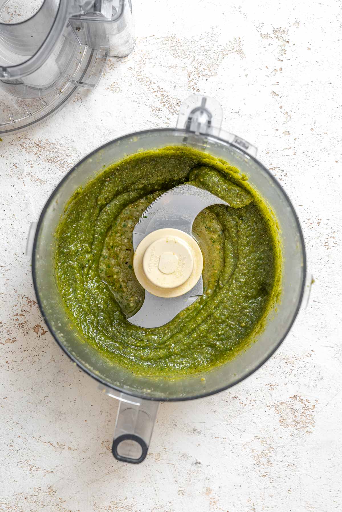 Process shot showing ingredients for Easy Walnut Pesto in food processor.