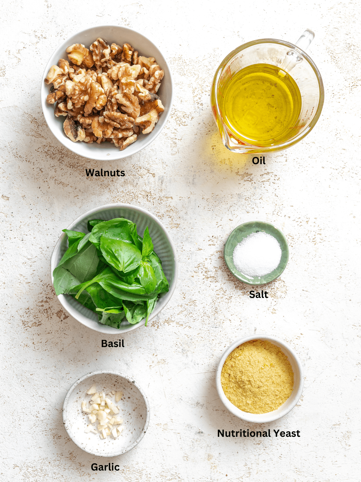 Ingredients for Easy Walnut Pesto measured out on a white surface.