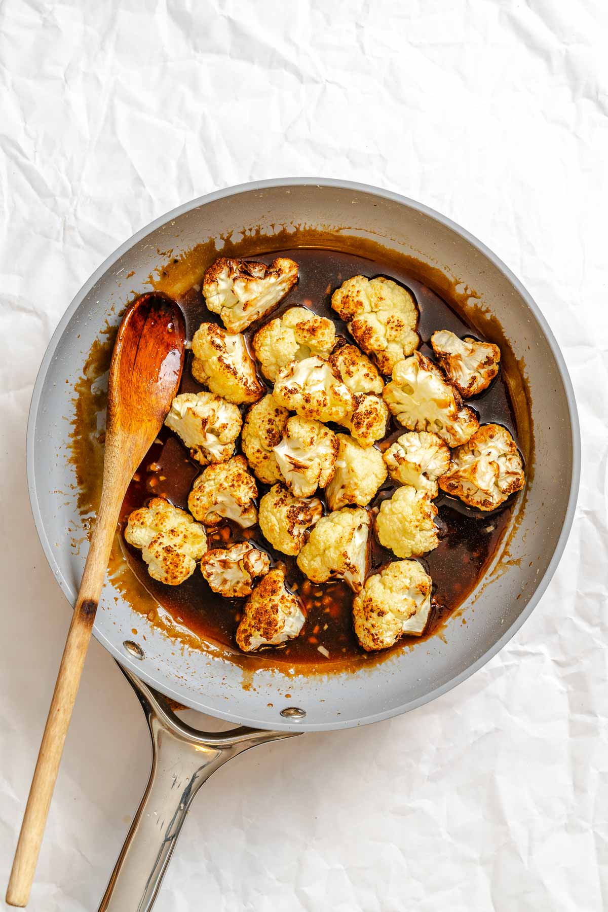 Process shot showing using a spoon to mix cauliflower in a bowl.
