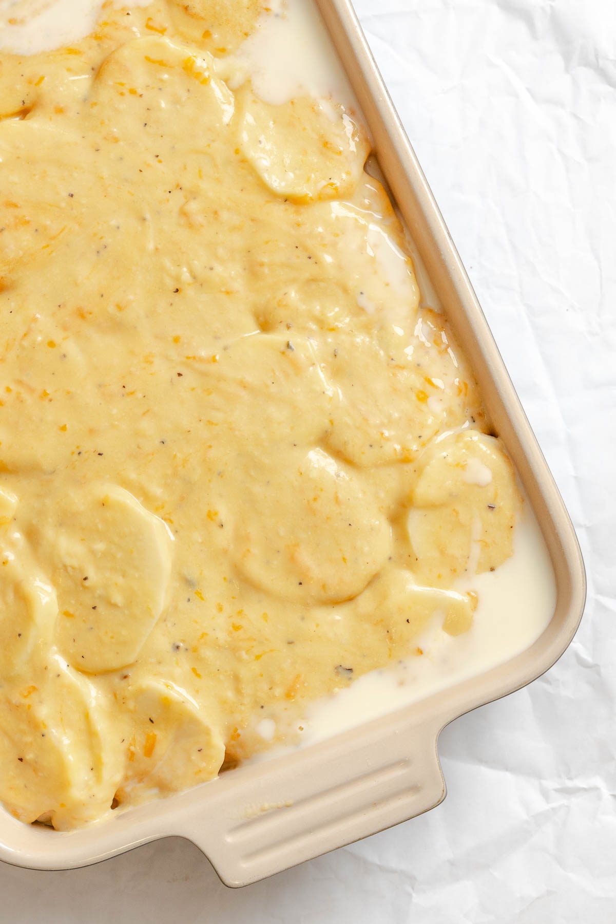 Process shot showing potatoes added to baking dish.
