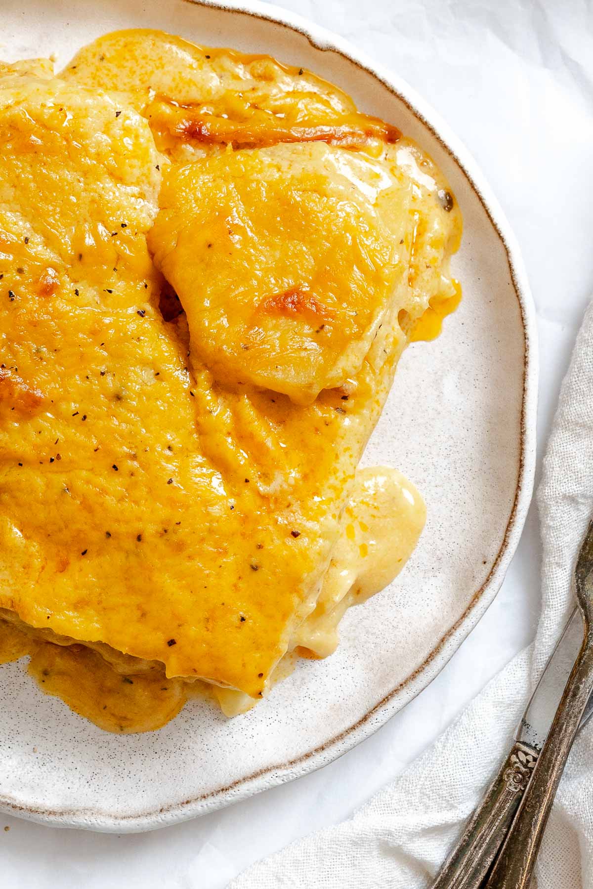 Completed Vegan Scalloped Potatoes on a plate on a white surface.
